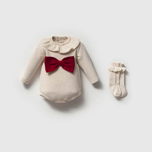 Baby outfit with beige romper and red bow, paired with socks on a light gray background