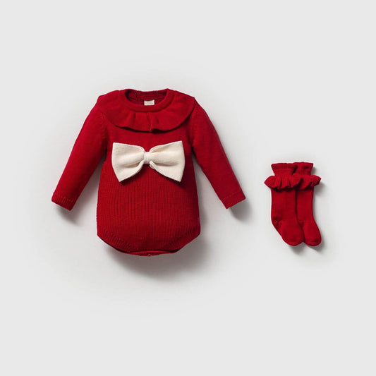 Red baby outfit with a white bow and matching red socks on a light gray background